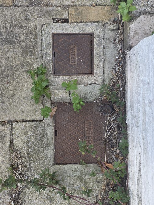 Two external water stop tap covers in paving